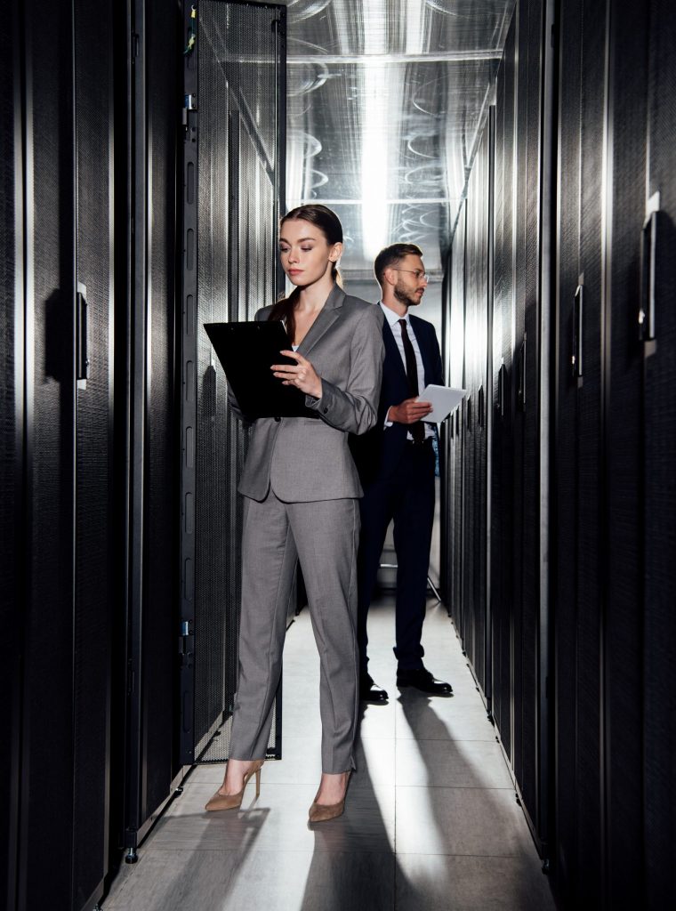 selective focus of attractive businesswoman holding clipboard near bearded businessman in data